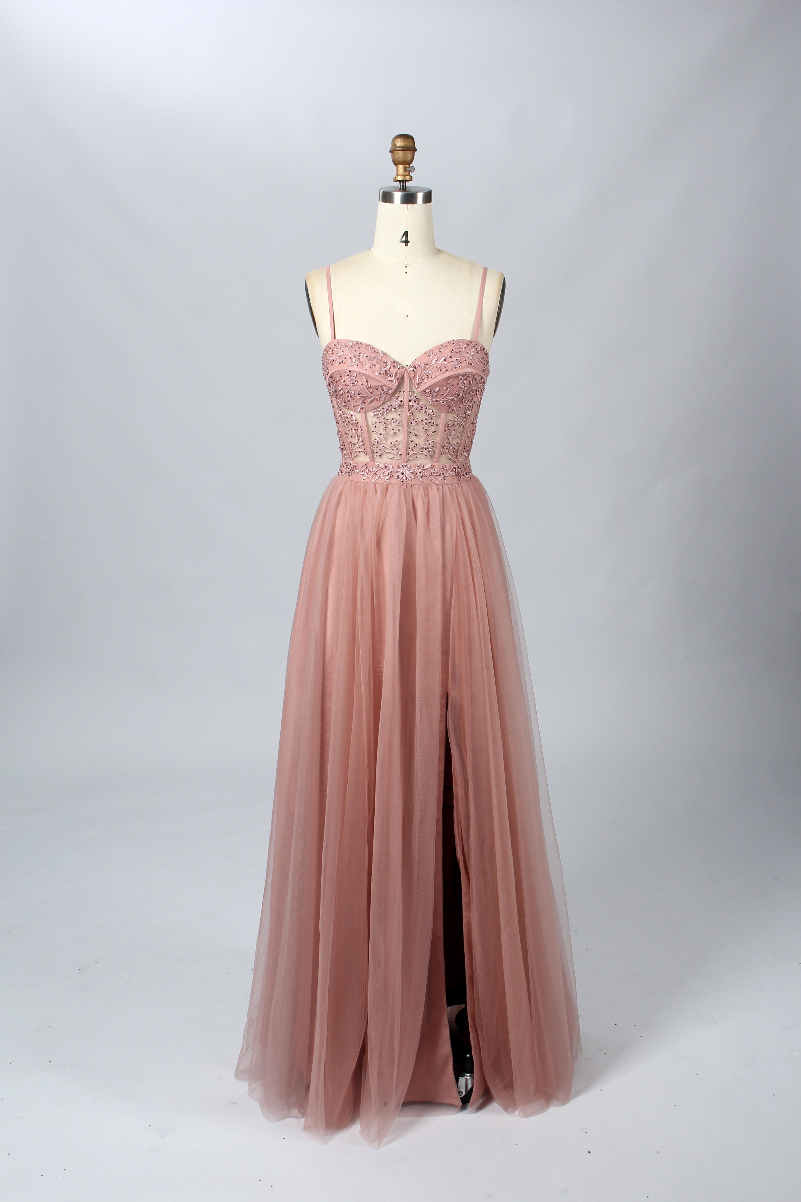 Photograph of a black, lace-trimmed, strapless gown with a sweetheart neckline and a full, flowing tulle skirt. The dress is displayed on a white mannequin with a wooden stand against a plain, light beige background, creating a simple and elegant setting.32547c-2.7