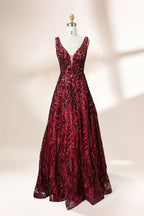 A photograph of a model dress on a dress form. The dress is a sleeveless, deep V-neck gown with a plunging neckline. It features a rich, deep red color with intricate, swirling black and red patterns, giving it a luxurious and elegant appearance. The background is a soft, neutral tone, with gentle shadows cast on the dress form.32625.1