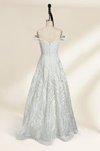 Photograph of a white, off-the-shoulder wedding gown displayed on a black dress form against a cream backdrop. The gown features intricate, swirling floral lace embroidery with a fitted bodice and a full, flared skirt, exuding elegance and sophistication. The dress form is centered, highlighting the gown's delicate detailing and flowing texture.32625b.2