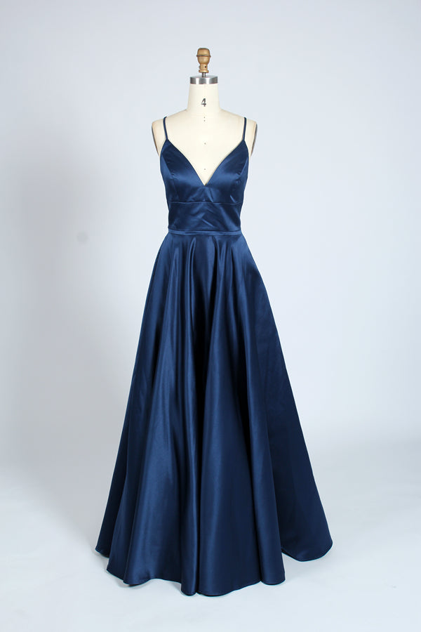 photograph, beautiful woman, long blonde hair, wavy hair, fair skin, blue satin gown, floor-length dress, V-neck, sleeveless, elegant, standing pose, white background, studio lighting, shadows on wall, confident expression, red lipstick, glamorous, high-fashion, evening wear, full body shot, no accessories, simple backdrop, clean lines, minimalistic, modern style, fashionable, chic, sophisticated, elegant, high-quality image, sharp details.32636-12