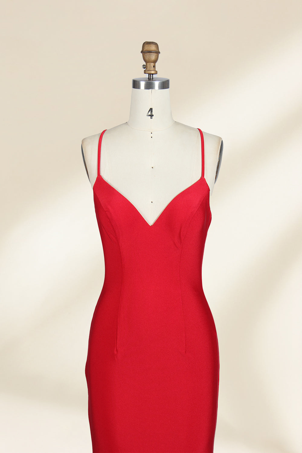 A photograph of a red, floor-length, strapless evening gown displayed on a white dress form with a wooden neck and arm rods. The gown has a fitted bodice and a flowing, slightly flared skirt. The background is a plain, light beige, emphasizing the dress's vibrant color and elegant design.32637.3