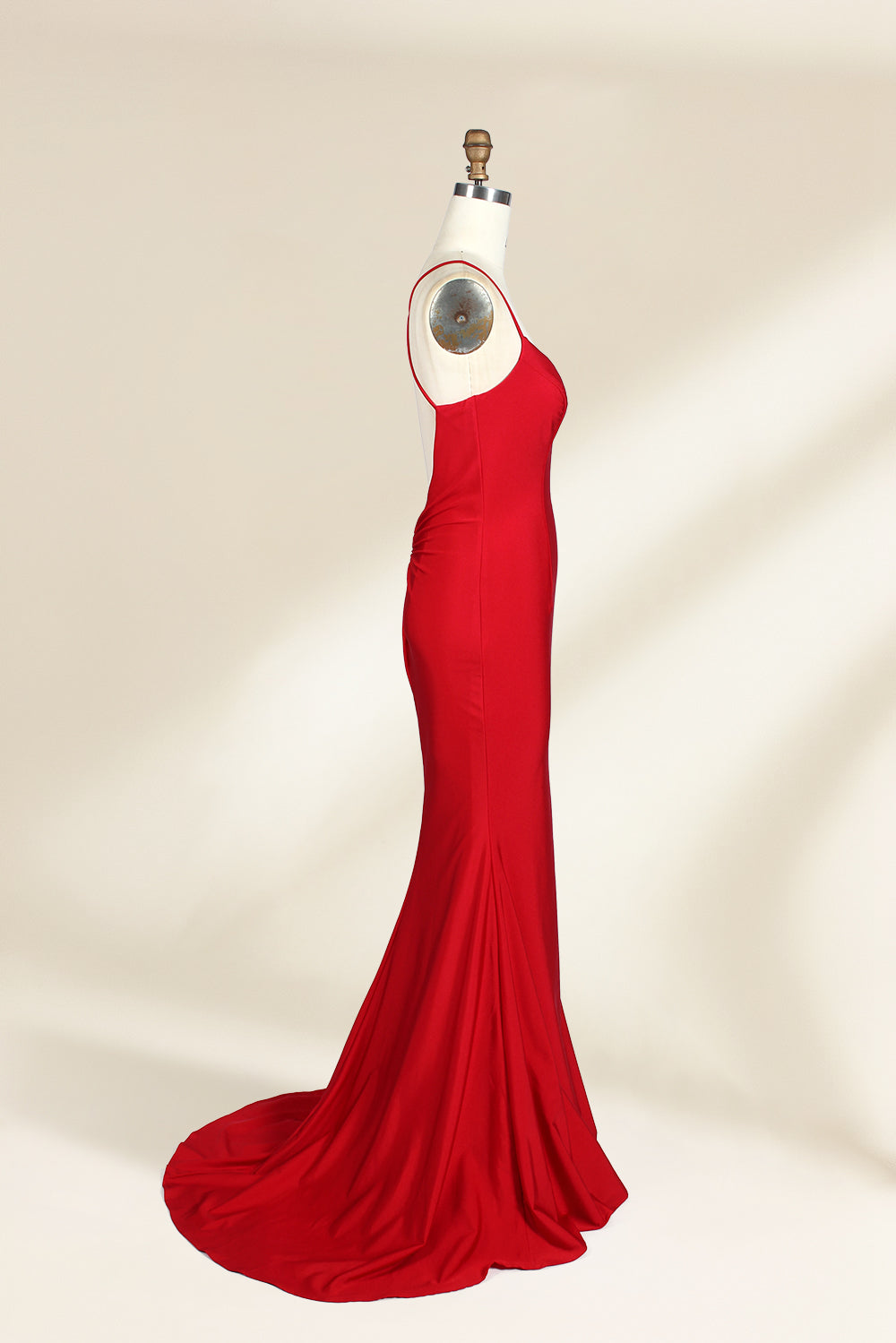 A photograph of a red, floor-length, strapless evening gown displayed on a white dress form with a wooden neck and arm rods. The gown has a fitted bodice and a flowing, slightly flared skirt. The background is a plain, light beige, emphasizing the dress's vibrant color and elegant design.32637.4