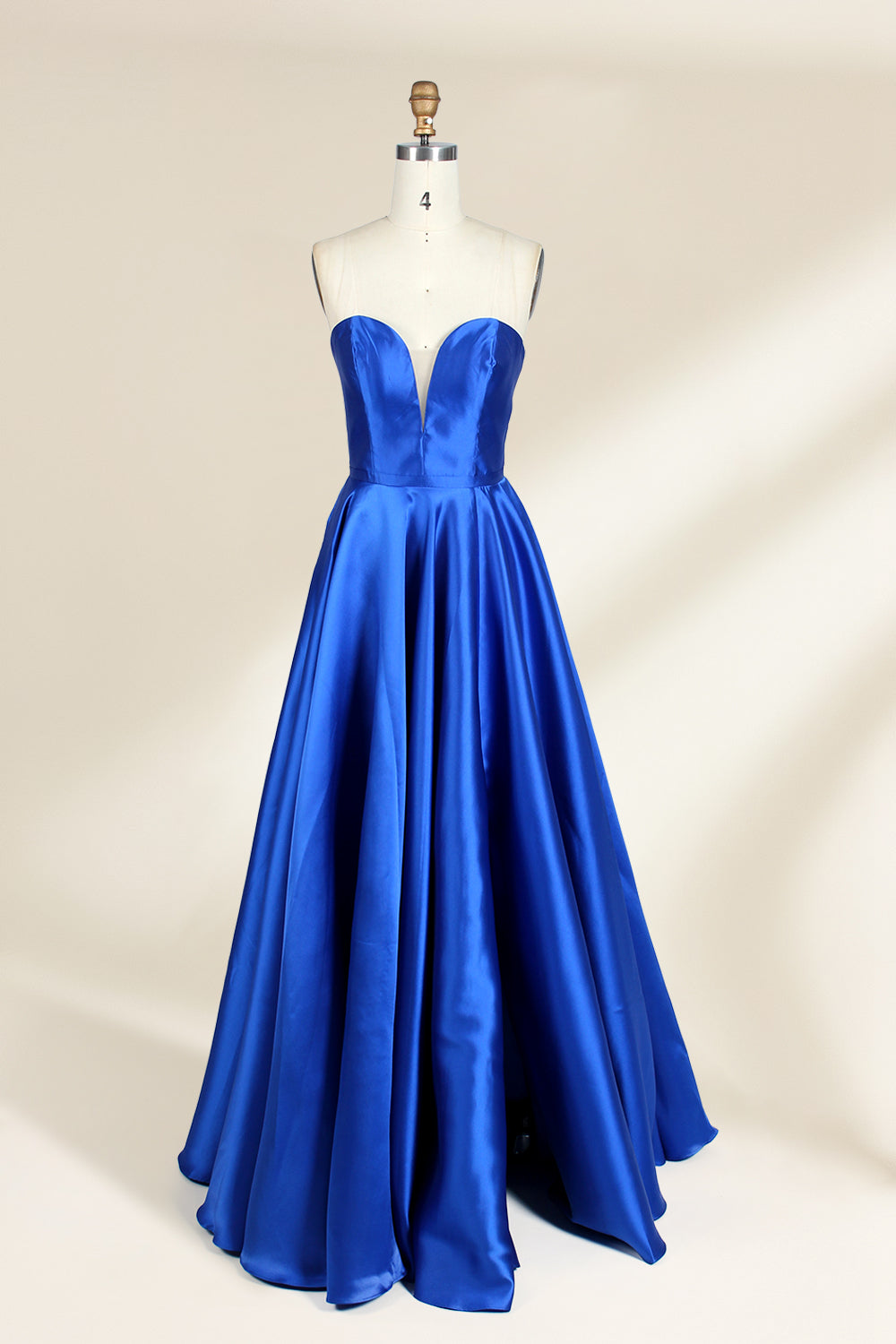 A photograph of a mannequin wearing a strapless, floor-length blue satin gown with a sweetheart neckline. The dress features a fitted bodice and a voluminous skirt. The mannequin stands against a plain, cream-colored background, highlighting the dress's elegant, flowing fabric and vibrant color.32638.1