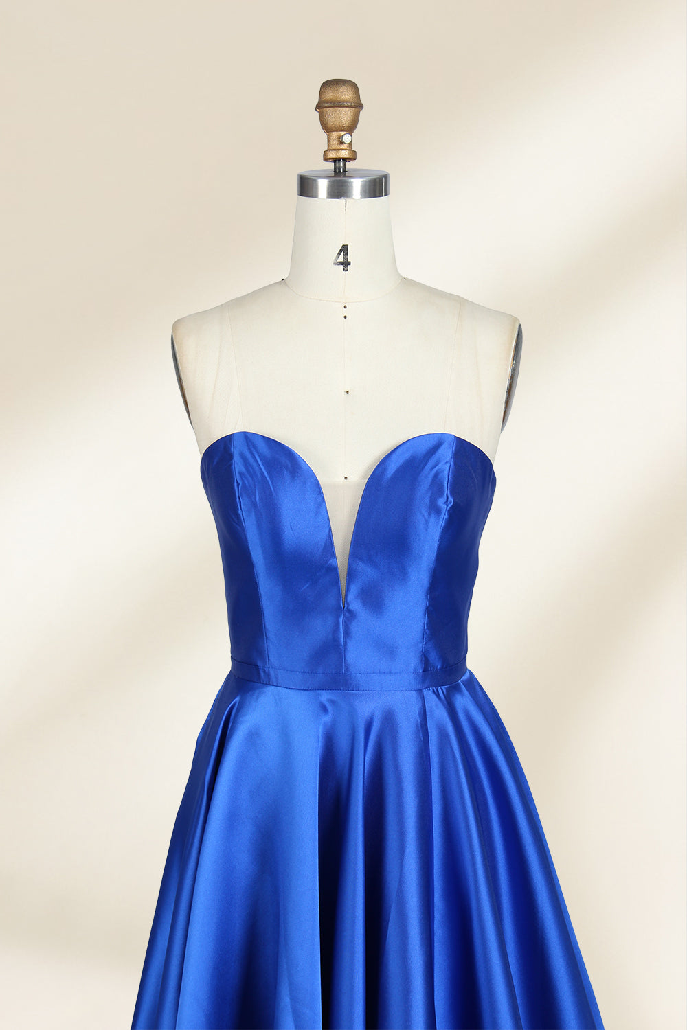 A photograph of a mannequin wearing a strapless, floor-length blue satin gown with a sweetheart neckline. The dress features a fitted bodice and a voluminous skirt. The mannequin stands against a plain, cream-colored background, highlighting the dress's elegant, flowing fabric and vibrant color.32638.2