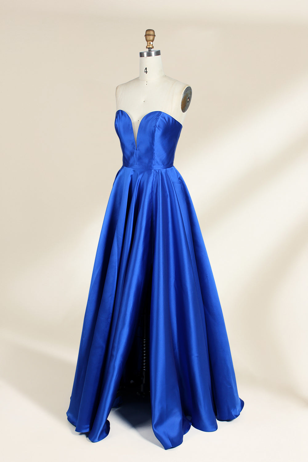 A photograph of a mannequin wearing a strapless, floor-length blue satin gown with a sweetheart neckline. The dress features a fitted bodice and a voluminous skirt. The mannequin stands against a plain, cream-colored background, highlighting the dress's elegant, flowing fabric and vibrant color.32638.3