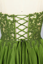 Photograph of an elegant, strapless gown displayed on a mannequin. The gown features a green, satin bodice adorned with intricate lace detailing and a full, floor-length skirt. The background is a soft, neutral gradient, enhancing the gown's vibrant green color. The mannequin is positioned centrally, with the gown's luxurious texture and refined craftsmanship prominently showcased.32639.3