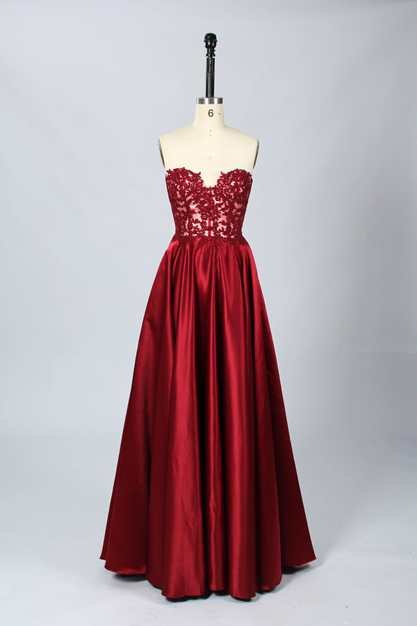 Photograph of an elegant, strapless gown displayed on a mannequin. The gown features a green, satin bodice adorned with intricate lace detailing and a full, floor-length skirt. The background is a soft, neutral gradient, enhancing the gown's vibrant green color. The mannequin is positioned centrally, with the gown's luxurious texture and refined craftsmanship prominently showcased.32639.8