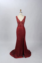 A photograph of a black, floor-length evening gown with a deep V-neck and lace detailing, featuring a thigh-high slit on the left side. The dress is displayed on a white mannequin with a black stand against a soft, beige background with diffused lighting creating gentle shadows. The gown exudes elegance and sophistication.32645.7
