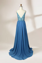 A photograph of a mannequin wearing a floor-length, blue evening gown. The dress features a deep V-neckline adorned with intricate beading, a fitted bodice, and a flowing, high slit skirt. The background is a plain, light beige color, highlighting the gown's elegant design and delicate textures.32656.2