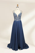 Photograph of a mannequin showcasing an elegant, floor-length evening gown. The gown features a deep V-neckline adorned with intricate blue floral embroidery, transitioning into a flowing, dark blue chiffon skirt. The mannequin stands against a plain, cream-colored backdrop. The dress exudes sophistication and luxury, perfect for formal events.01