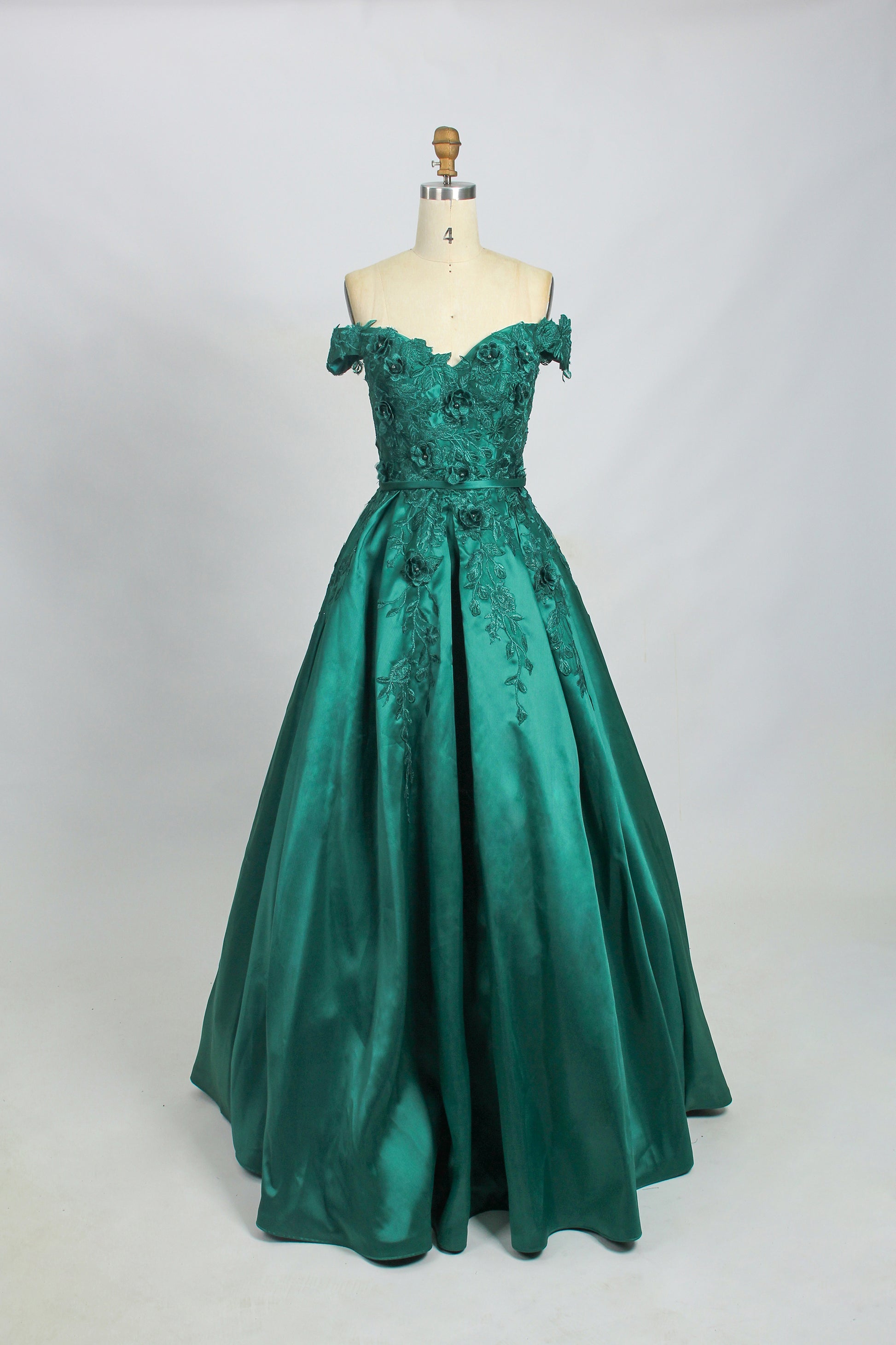 photograph of a mannequin wearing a teal off-the-shoulder ball gown, intricate floral embroidery on the bodice, full-length skirt with a slight sheen, elegant and luxurious, white background, simple studio setting, no other objects or people, fashion photography, high-quality image, detailed textures, soft lighting, fashion model stand, full body view, classic and sophisticated style