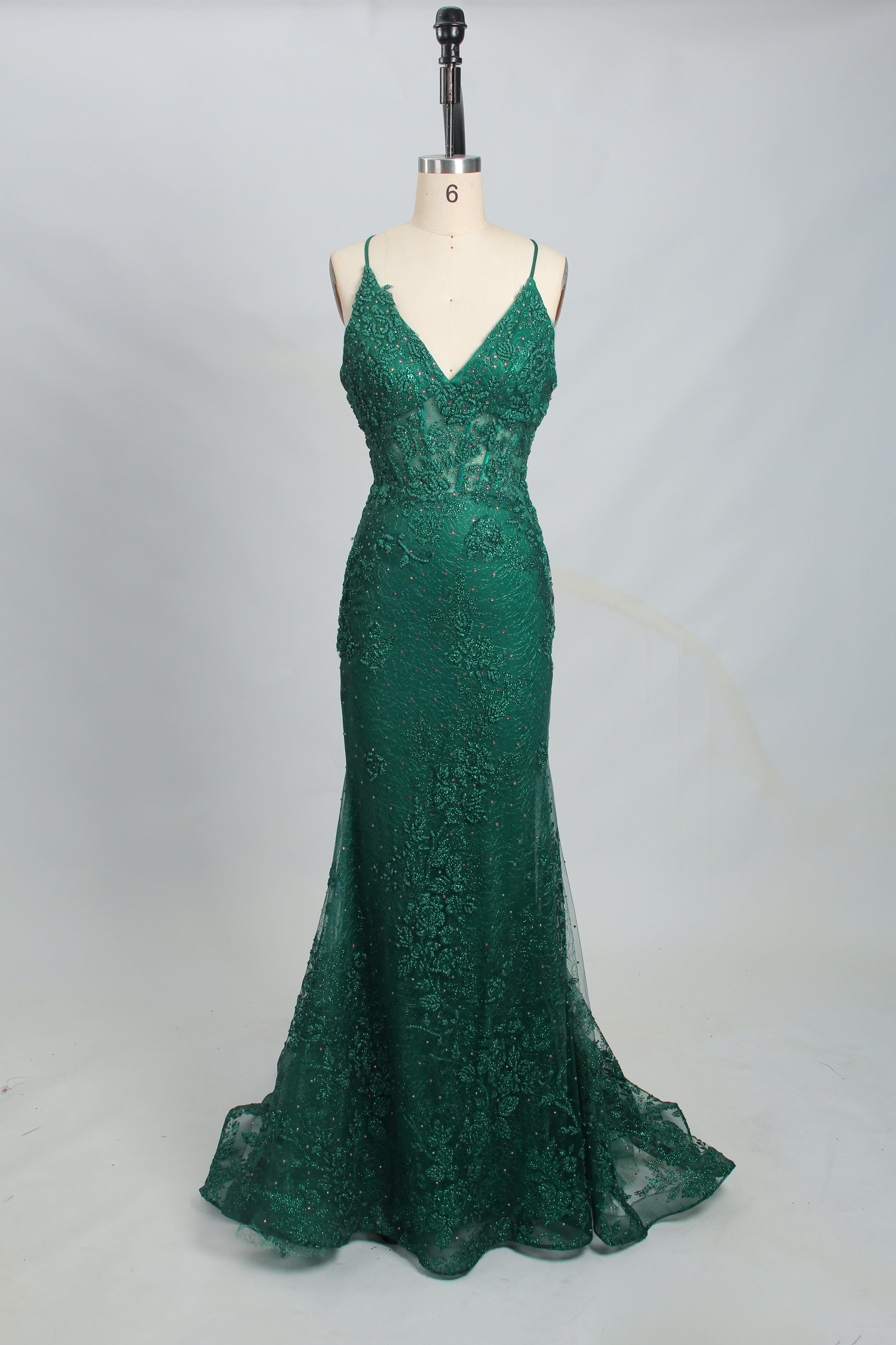 photograph of elegant green sequin evening gown, draped on mannequin, floor-length, fitted bodice, V-neckline, spaghetti straps, shimmering texture, dark green color, smooth fabric, studio background, soft lighting, minimalist setting, no accessories, no jewelry, no shoes, no visible face, neutral backdrop, simple and classy, fashion photography, high-quality image, detailed texture, sophisticated style, evening wear, formal attire, dress on display