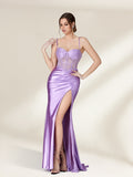 A photograph of a young woman with light skin and brown hair styled in an elegant updo, wearing a shimmering, floor-length, lavender satin gown with a high slit and intricate lace detailing. She stands confidently against a plain, beige background, exuding sophistication and grace.32738-01
