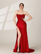 photograph of a beautiful woman, standing in front of a plain white background, wearing a stunning red strapless gown with a high slit, intricate lace detailing on the bodice, long flowing skirt, elegant black high heels, long legs, brunette hair styled in an updo, confident pose, soft lighting, shadows on the wall, modern fashion, sophisticated, glamorous, high fashion, elegant attire