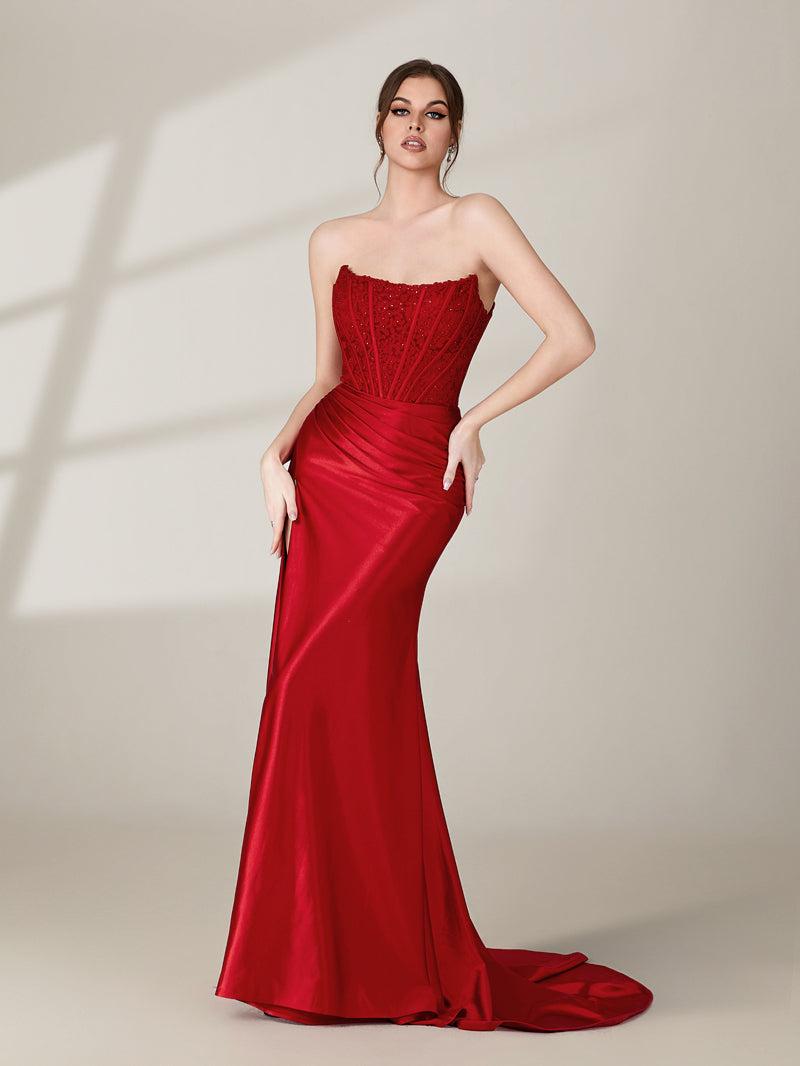 photograph of a beautiful woman, standing in front of a plain white background, wearing a stunning red strapless gown with a high slit, intricate lace detailing on the bodice, long flowing skirt, elegant black high heels, long legs, brunette hair styled in an updo, confident pose, soft lighting, shadows on the wall, modern fashion, sophisticated, glamorous, high fashion, elegant attire