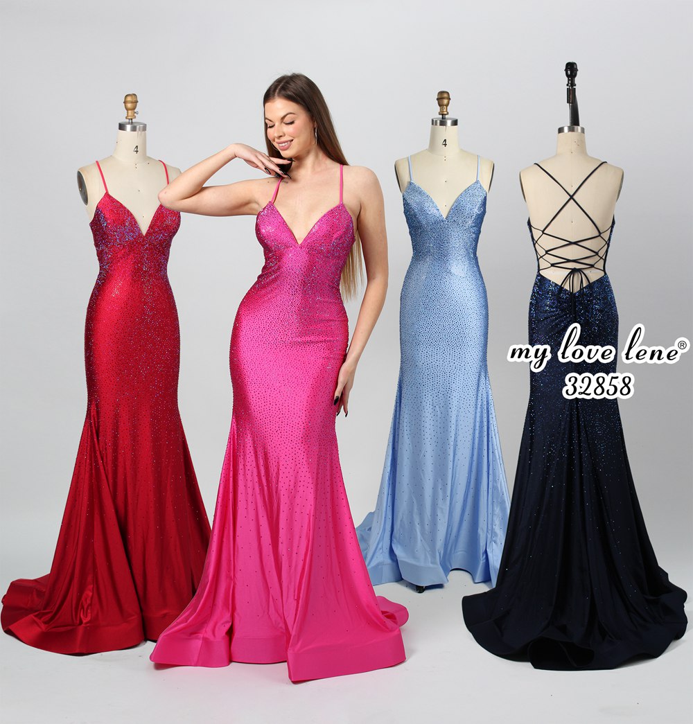 This photograph features three mannequins showcasing elegant evening gowns against a plain white background. The central mannequin wears a bright pink gown with intricate beadwork, while the left one dons a deep red gown with a similar design. The right mannequin is adorned in a royal blue gown with a crisscross lace back. A woman stands between the mannequins, wearing the pink gown, smiling confidently. The dresses are sequined and form-fitting, emphasizing their glamorous appeal.