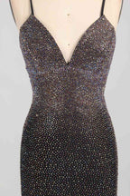 Photograph of a woman's torso wearing a form-fitting, black sequined dress with a deep V-neckline and spaghetti straps. The dress sparkles with a mix of small, shimmering sequins, creating a luxurious, textured appearance. The woman's skin tone is light, and her arms are raised above her head, slightly visible at the top of the image. The background is a plain, light grey, ensuring the focus remains on the dress. The overall style is elegant and glamorous, suitable for formal occasions.