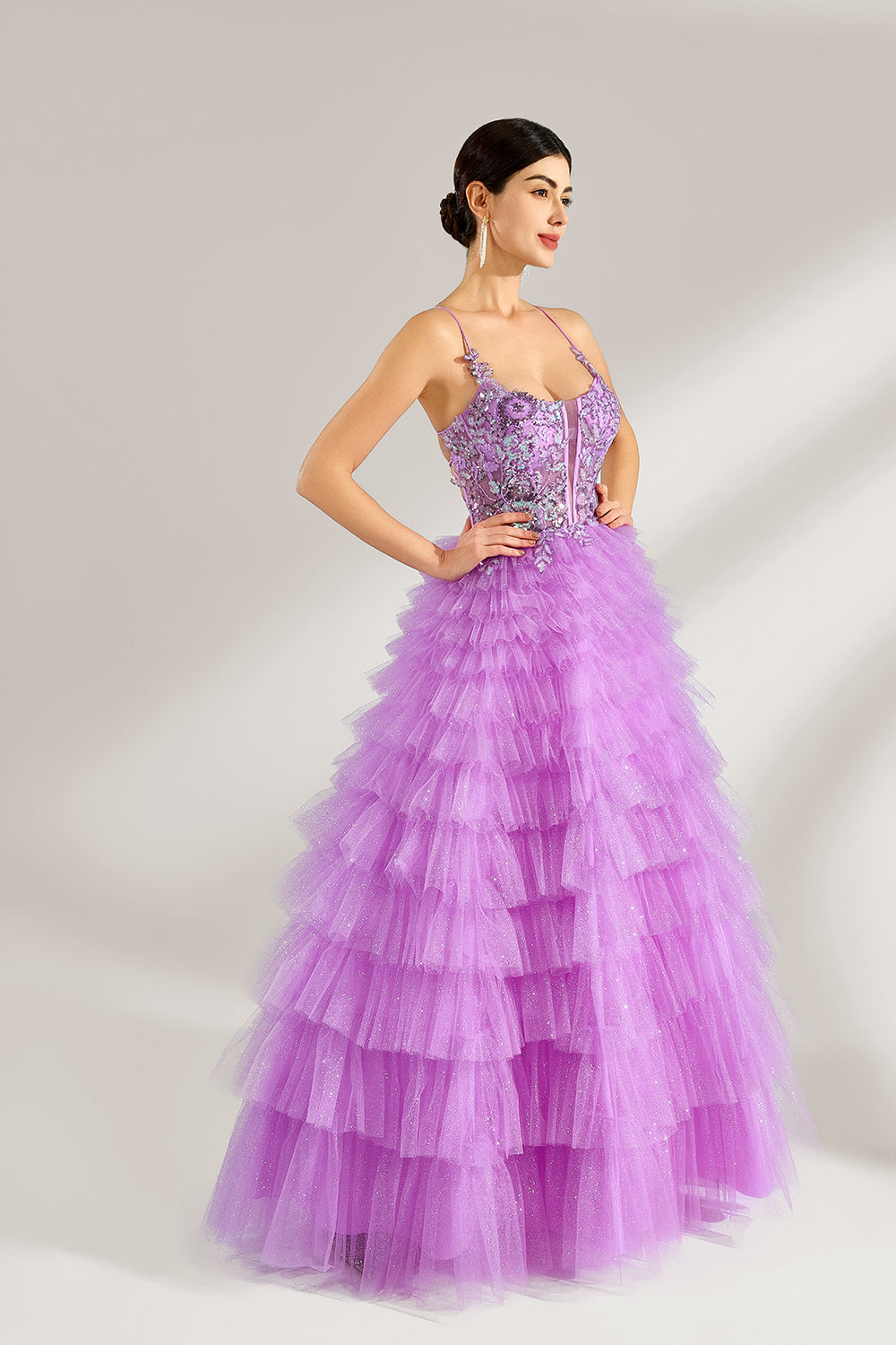 A woman with sleek dark hair and a poised stance wears a light - purple tulle gown. It has thin straps, a lace - detailed bodice, and a tiered, voluminous skirt. Paired with understated heels, the outfit radiates elegance, perfect for formal events like galas or proms.4
