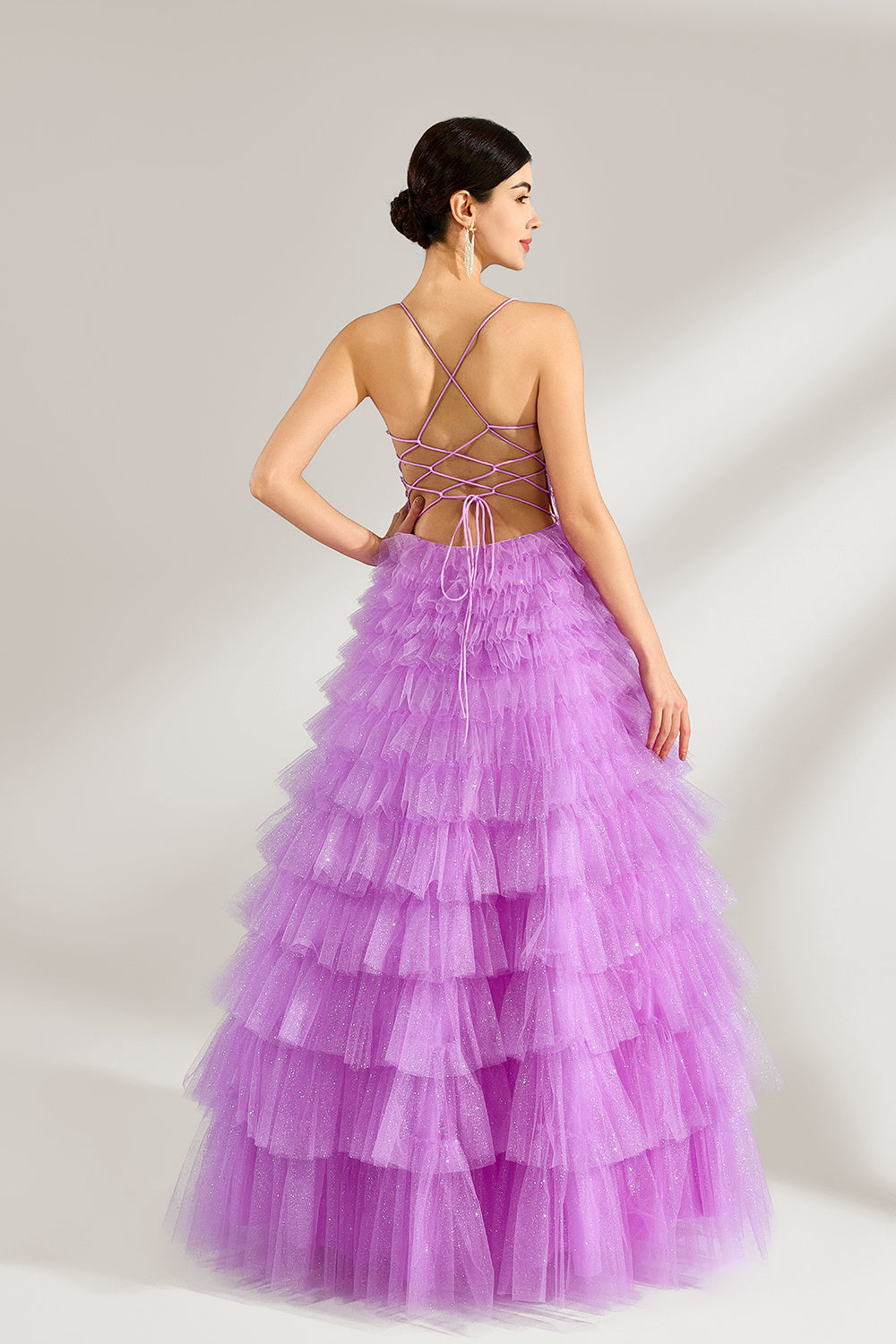 A woman with sleek dark hair and a poised stance wears a light - purple tulle gown. It has thin straps, a lace - detailed bodice, and a tiered, voluminous skirt. Paired with understated heels, the outfit radiates elegance, perfect for formal events like galas or proms.6
