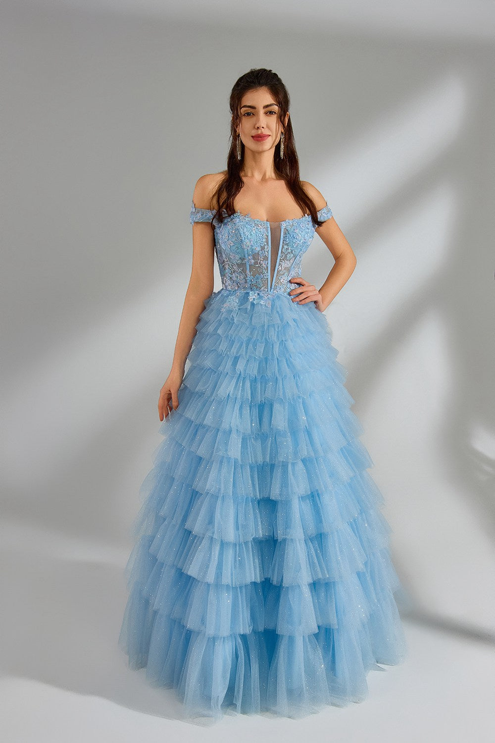 This image showcases a woman in a voluminous, blue tulle gown with intricate beadwork. The soft lighting and delicate textures evoke a romantic, ethereal quality. The gown's ruffled layers and sparkling embellishments suggest a fairytale aesthetic, reminiscent of the Romanticism movement's emphasis on beauty and emotion.
