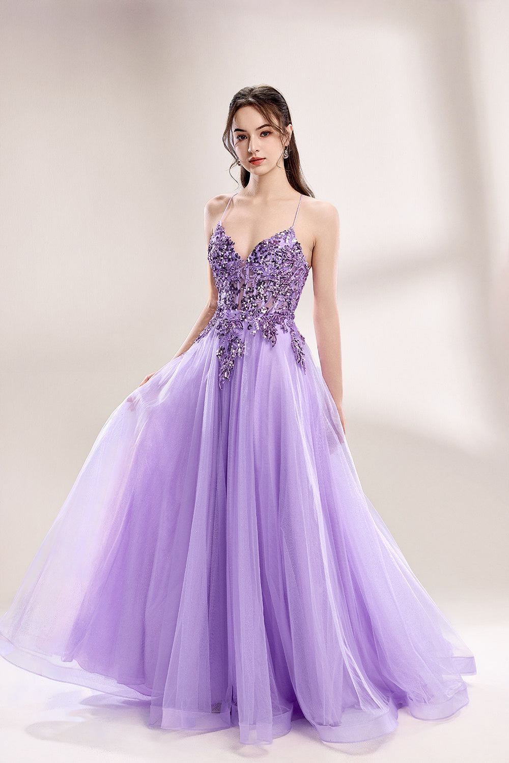 photograph of a young woman wearing a beautiful, floor-length, lavender ball gown with intricate sequin detailing on the bodice, sheer tulle skirt, spaghetti straps, long brown hair, fair skin, standing in a soft lit studio, neutral background, elegant, sophisticated, dreamy, fashion, glamour, full body shot, high quality, fashion photography, stylish, feminine, graceful, classy, modern, delicate, light, airy.33040-01