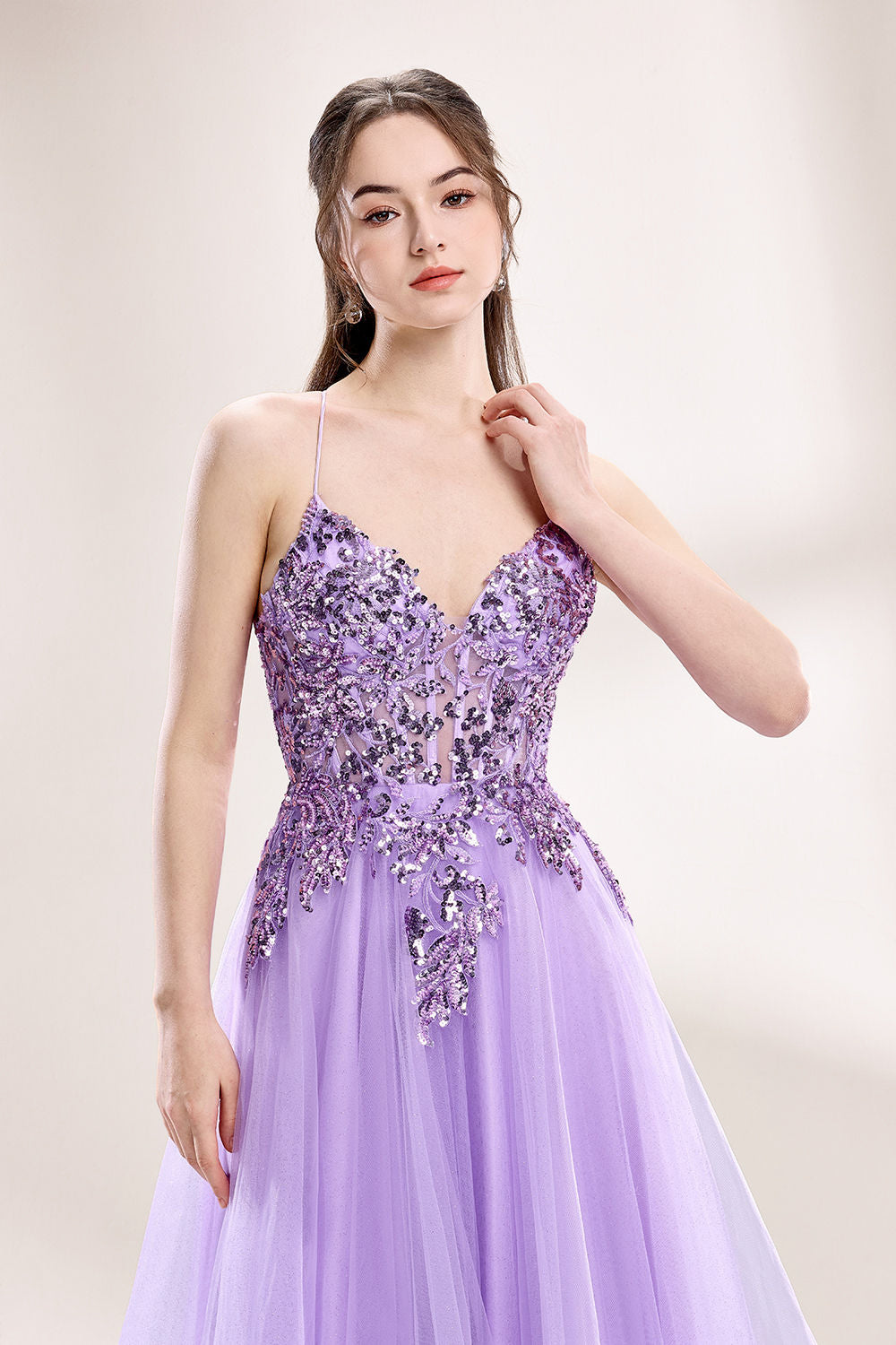 photograph of a young woman wearing a beautiful, floor-length, lavender ball gown with intricate sequin detailing on the bodice, sheer tulle skirt, spaghetti straps, long brown hair, fair skin, standing in a soft lit studio, neutral background, elegant, sophisticated, dreamy, fashion, glamour, full body shot, high quality, fashion photography, stylish, feminine, graceful, classy, modern, delicate, light, airy.33040-03