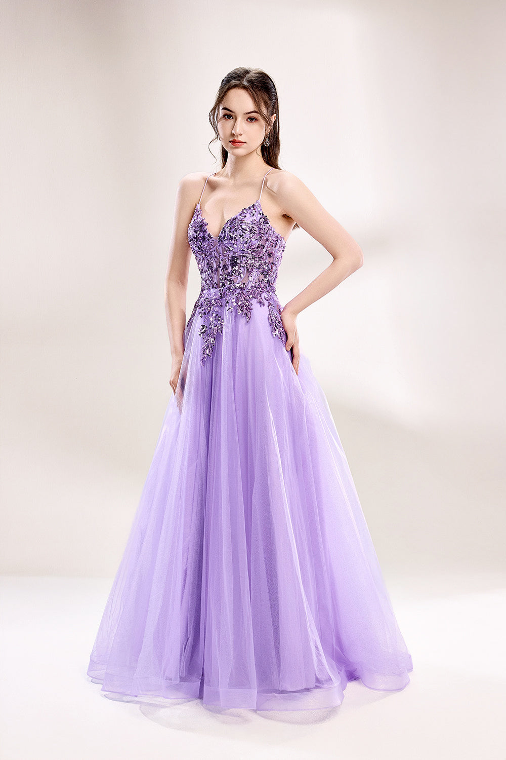 photograph of a young woman wearing a beautiful, floor-length, lavender ball gown with intricate sequin detailing on the bodice, sheer tulle skirt, spaghetti straps, long brown hair, fair skin, standing in a soft lit studio, neutral background, elegant, sophisticated, dreamy, fashion, glamour, full body shot, high quality, fashion photography, stylish, feminine, graceful, classy, modern, delicate, light, airy.33040-04