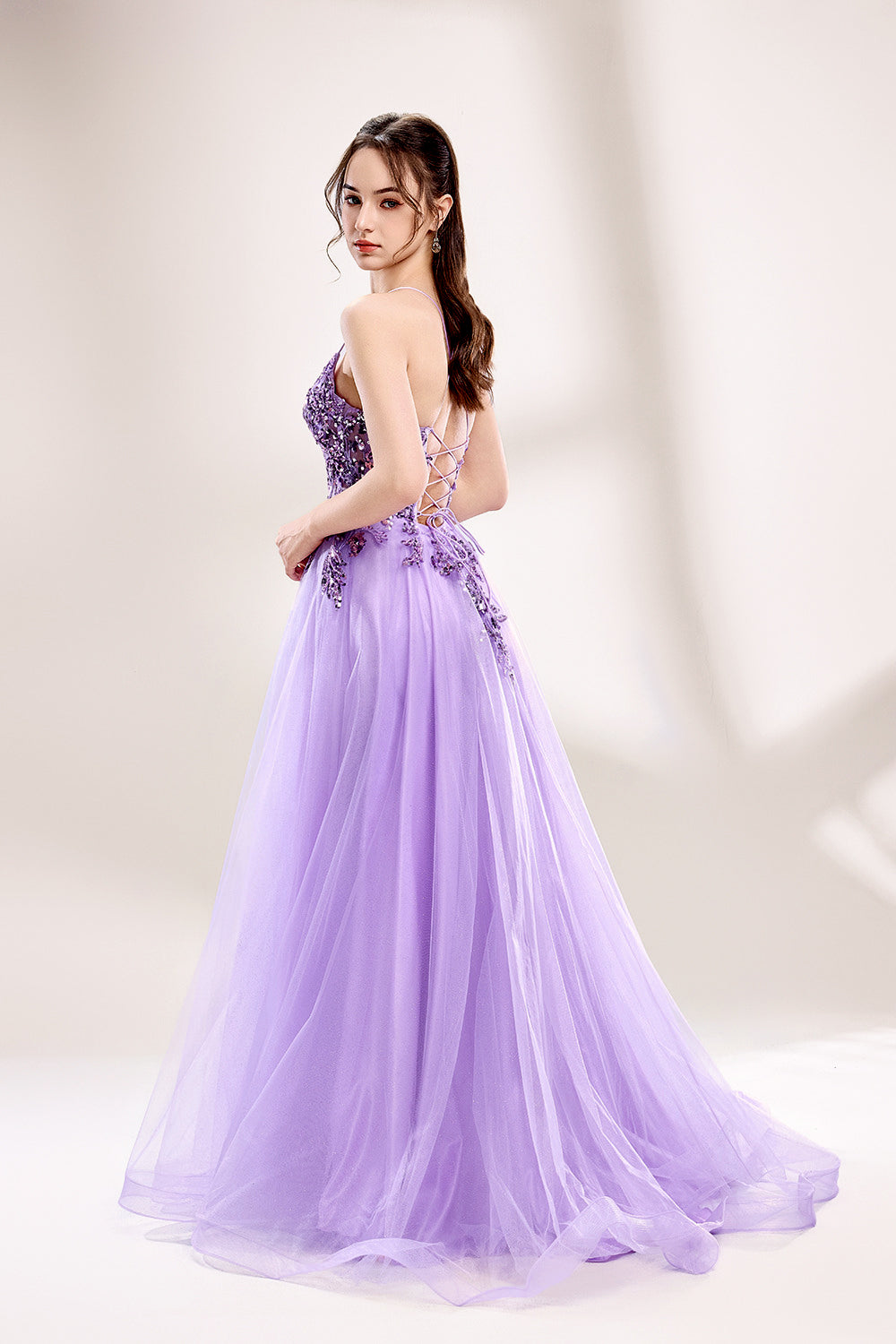 photograph of a young woman wearing a beautiful, floor-length, lavender ball gown with intricate sequin detailing on the bodice, sheer tulle skirt, spaghetti straps, long brown hair, fair skin, standing in a soft lit studio, neutral background, elegant, sophisticated, dreamy, fashion, glamour, full body shot, high quality, fashion photography, stylish, feminine, graceful, classy, modern, delicate, light, airy.33040-06