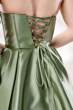 photograph of a woman in a backless, strapless, emerald green satin gown, standing against a white studio background, soft shadows, elegant, classic style, smooth fabric texture, hair in an elegant updo, long flowing gown, no visible accessories, minimalistic setting, studio lighting, elegant and sophisticated, full-length dress, high slit, backless design, full body shot, serene and graceful atmosphere.33110B-06