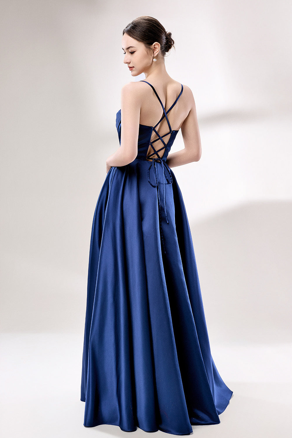photo of a beautiful young woman, Asian descent, fair skin, long black hair in a low bun, wearing a stunning royal blue satin gown, corset-style top, full skirt, elegant and classy, standing against a plain white background, soft lighting, minimalistic setting, hands behind her back, confident pose, fashion photography, high-quality image, no watermarks.33119-02