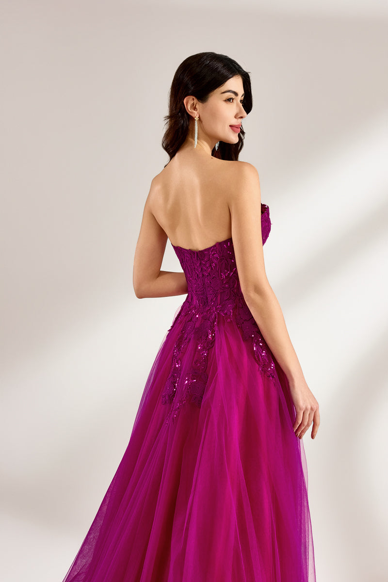 Photograph of a woman with long, dark hair in a strapless, vibrant magenta ball gown with a fitted bodice and a voluminous tulle skirt. The dress features a thigh-high slit on the left side and sparkling embellishments. She stands against a plain white background, exuding elegance and confidence.3321-05