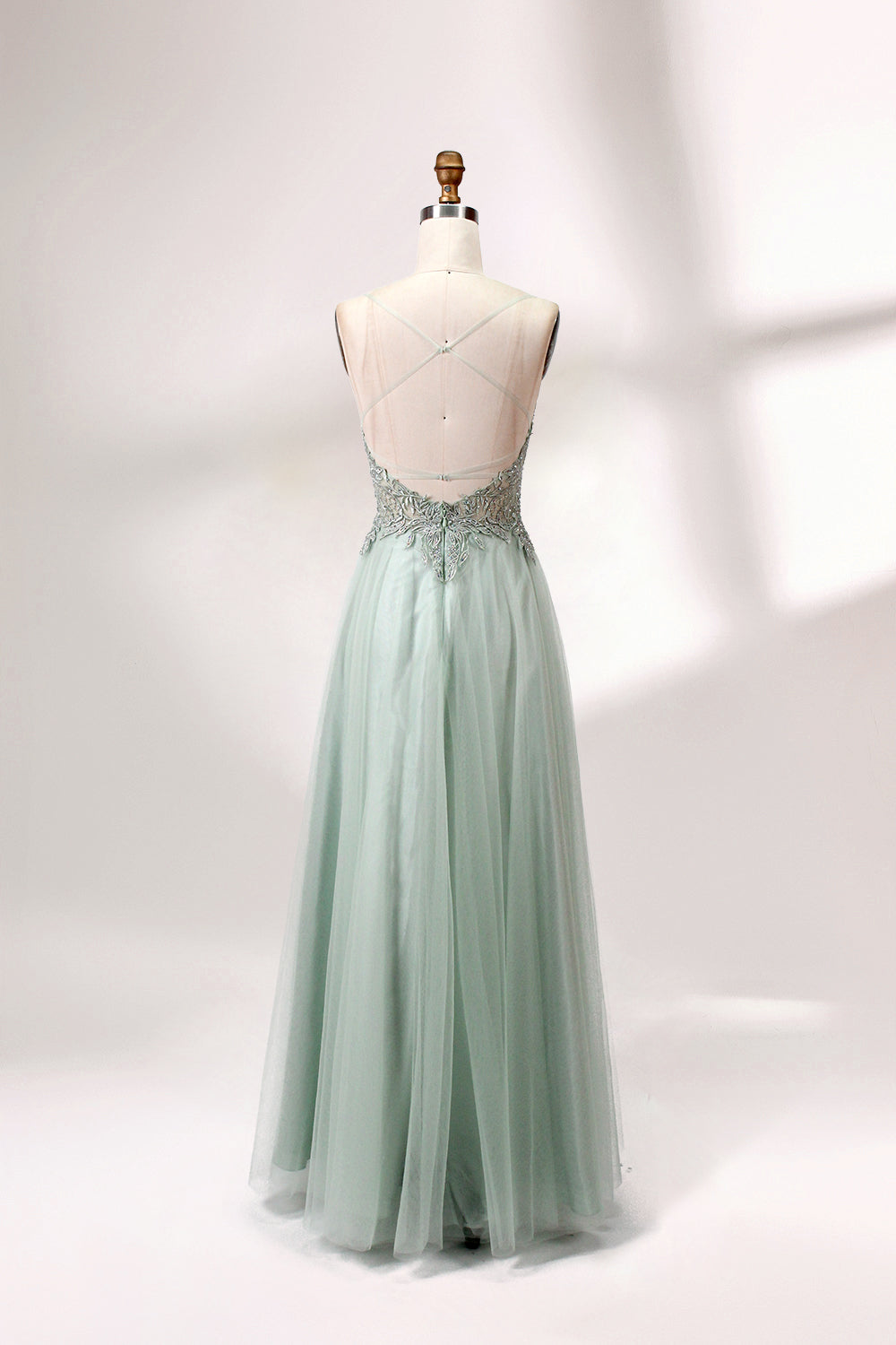 A mannequin showcases a light - green tulle gown with a lace - embroidered, sheer bodice. It has thin straps, a deep V - neckline, and a voluminous skirt. The delicate lace and flowing tulle create a romantic look, perfect for formal events like weddings or proms, exuding elegance.
2