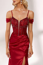 A woman stands against a light background, wearing a deep - red satin gown. It features off - shoulder sleeves, a beaded bodice, and a high side slit. The intricate bead patterns and ruched skirt create a glamorous look, perfect for formal events like galas or evening parties, exuding elegance and charm.5