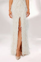 Illuminated by soft light, a woman captivates in a white feather - trimmed gown. It has thin straps, a V - neckline with intricate beadwork, and a high side slit. The glamorous design, with its feathery texture, creates an eye - catching and elegant look, perfect for formal events or red - carpet moments.6