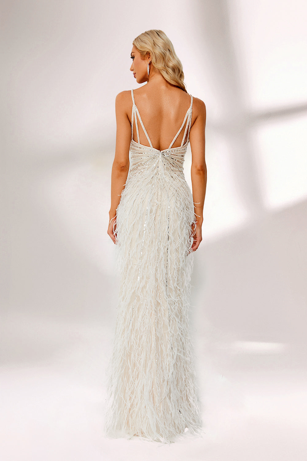 Illuminated by soft light, a woman captivates in a white feather - trimmed gown. It has thin straps, a V - neckline with intricate beadwork, and a high side slit. The glamorous design, with its feathery texture, creates an eye - catching and elegant look, perfect for formal events or red - carpet moments.2