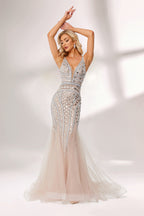 Bathed in soft light, a woman stuns in a nude - hued mermaid gown. It has thin straps, a deep V - neckline, and is covered with intricate silver geometric bead and sequin embroidery, plus a flowing tulle skirt. The shimmering details give off an opulent vibe, perfect for grand galas or red - carpet moments.1