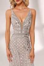 Bathed in soft light, a woman stuns in a nude - hued mermaid gown. It has thin straps, a deep V - neckline, and is covered with intricate silver geometric bead and sequin embroidery, plus a flowing tulle skirt. The shimmering details give off an opulent vibe, perfect for grand galas or red - carpet moments.6