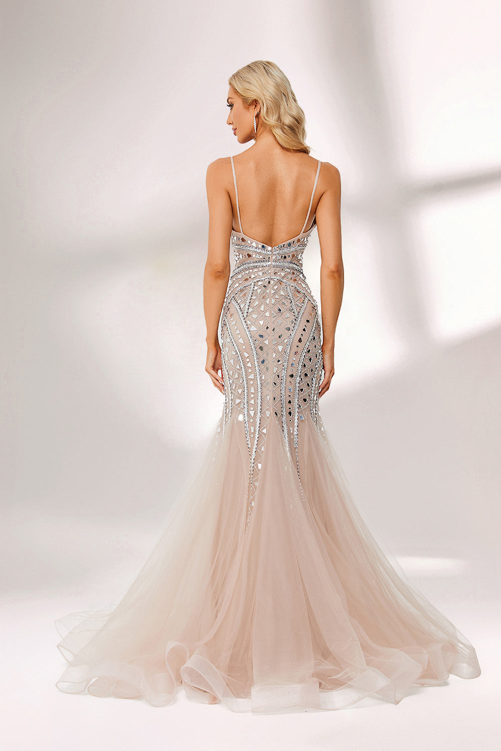 Bathed in soft light, a woman stuns in a nude - hued mermaid gown. It has thin straps, a deep V - neckline, and is covered with intricate silver geometric bead and sequin embroidery, plus a flowing tulle skirt. The shimmering details give off an opulent vibe, perfect for grand galas or red - carpet moments.2