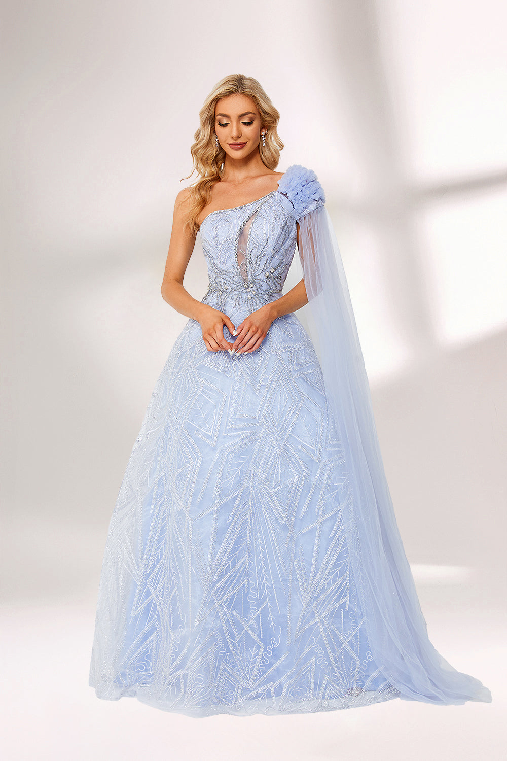 In soft lighting, a woman stuns in a light blue one - shoulder evening gown. It has a floral accent on the shoulder, a sheer cape - like detail, and intricate silver embroidery. The dreamy design creates an elegant and fairy - tale - like look, perfect for grand events.1