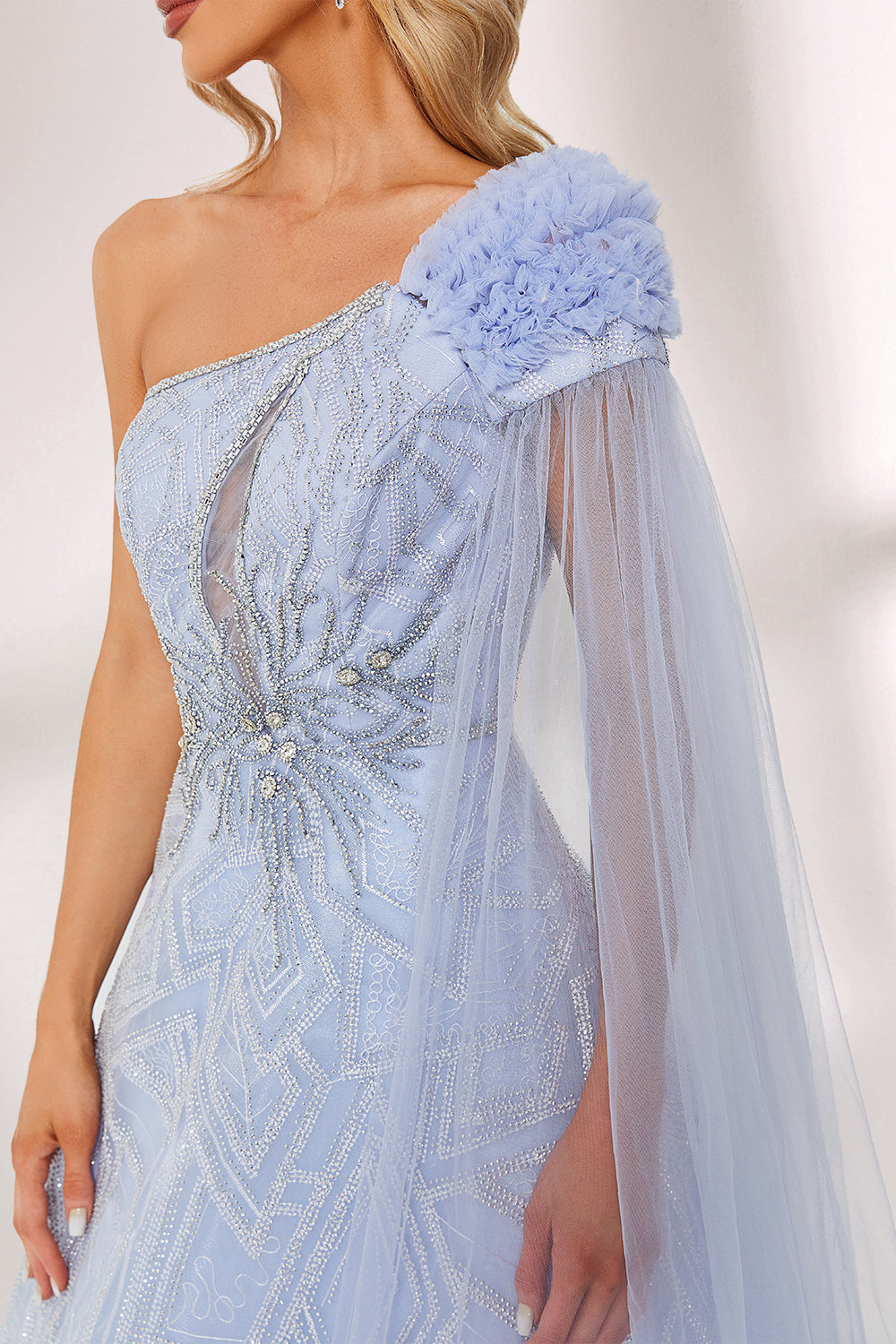 In soft lighting, a woman stuns in a light blue one - shoulder evening gown. It has a floral accent on the shoulder, a sheer cape - like detail, and intricate silver embroidery. The dreamy design creates an elegant and fairy - tale - like look, perfect for grand events.5