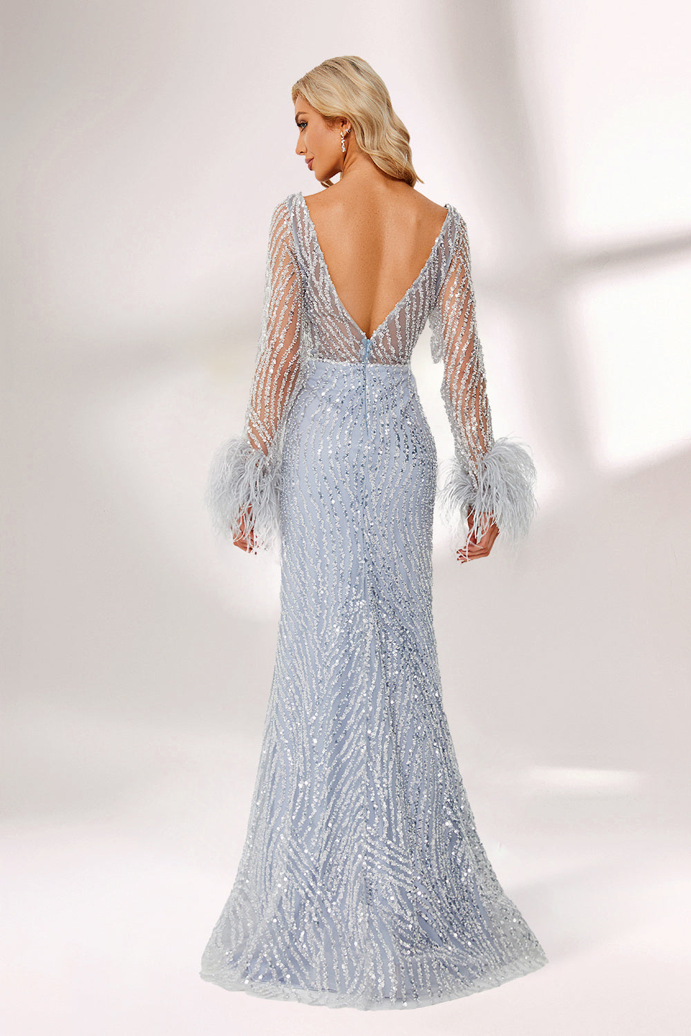 Set against a light backdrop, a woman dons a light - blue sequin gown with sheer sleeves and feather cuffs. It has a V - neckline, a mermaid - shaped skirt, and shimmering sequins. The unique feather details and sparkling fabric create a glamorous look, ideal for proms or formal evening events.2