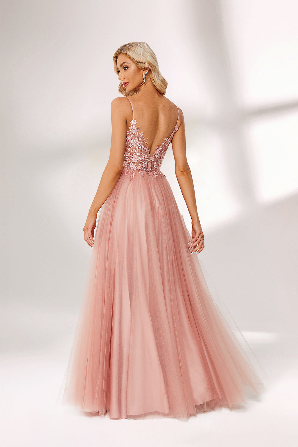A woman stands against a light background, wearing a pink tulle gown. It has thin straps, a deep V - neckline, and a voluminous skirt. The bodice features delicate floral lace embroidery, combining romance and elegance. Perfect for formal events like weddings or proms, it exudes charm.2