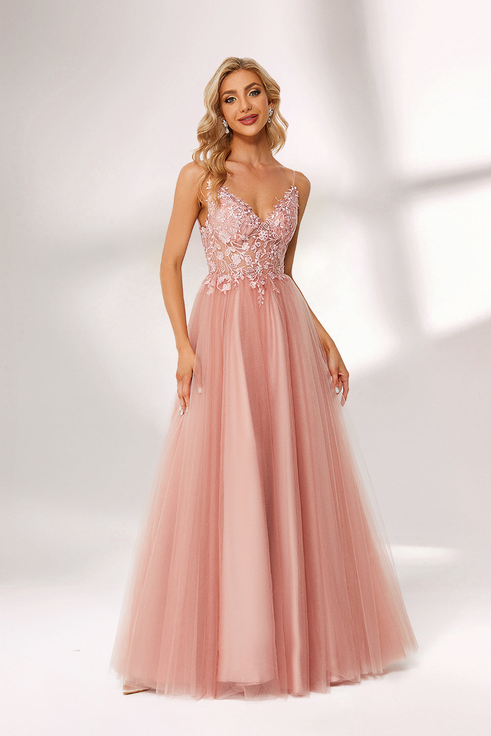 A woman stands against a light background, wearing a pink tulle gown. It has thin straps, a deep V - neckline, and a voluminous skirt. The bodice features delicate floral lace embroidery, combining romance and elegance. Perfect for formal events like weddings or proms, it exudes charm.4