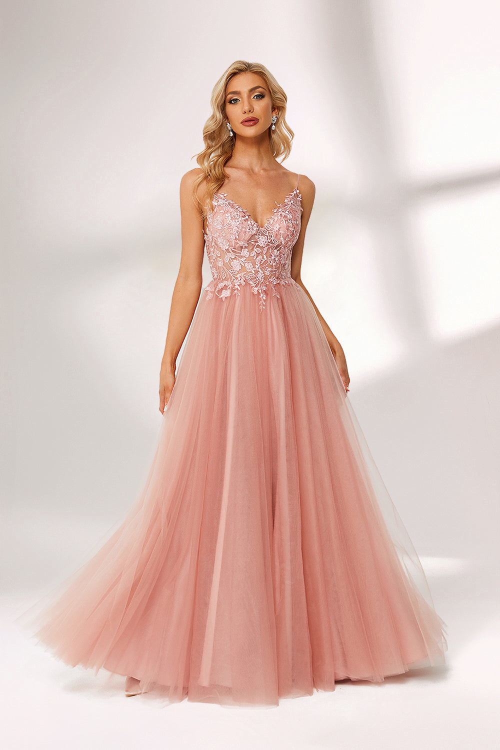 A woman stands against a light background, wearing a pink tulle gown. It has thin straps, a deep V - neckline, and a voluminous skirt. The bodice features delicate floral lace embroidery, combining romance and elegance. Perfect for formal events like weddings or proms, it exudes charm.1