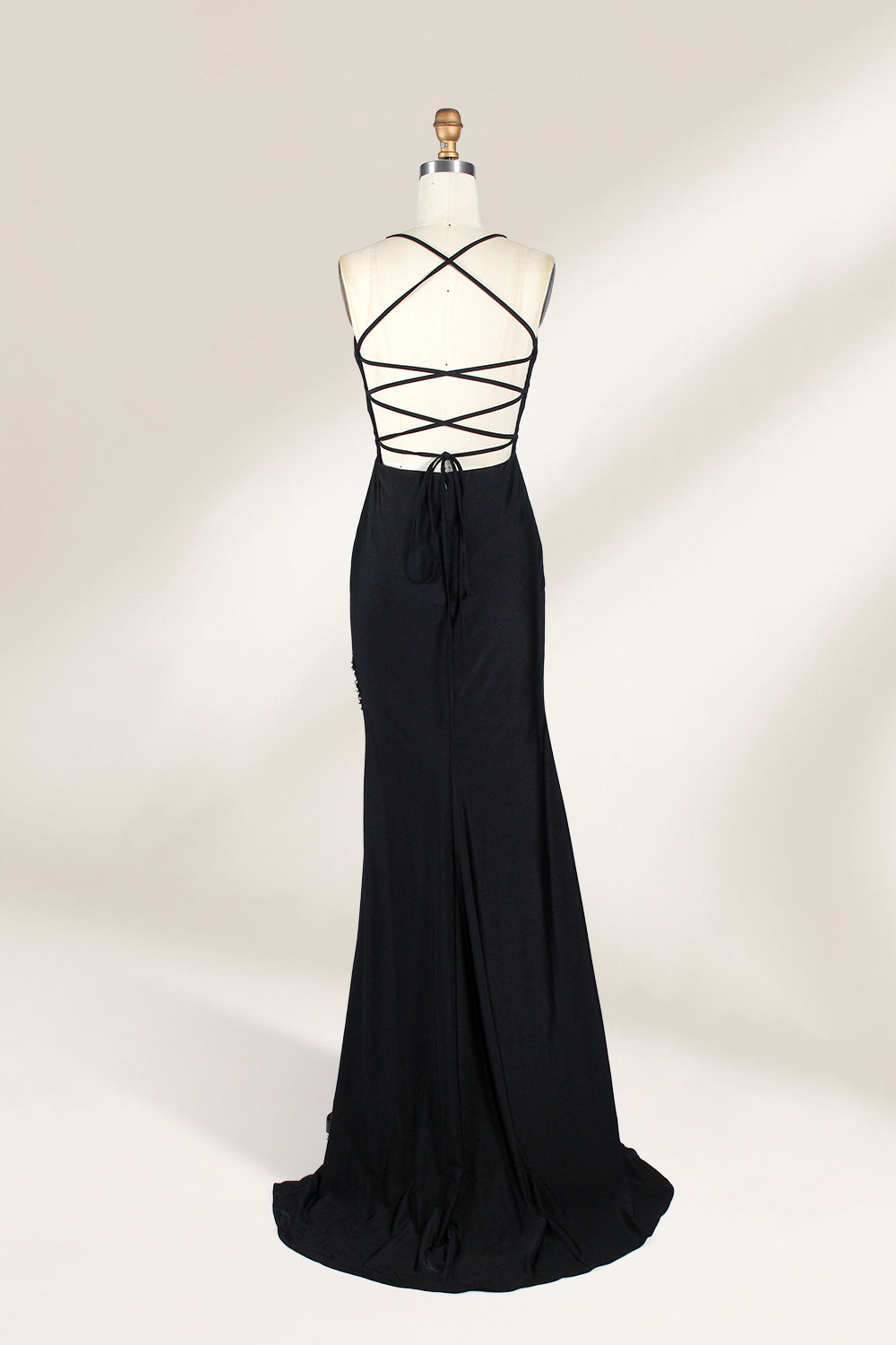 Displayed on a mannequin is a black evening gown. It features spaghetti straps, a deep V - neck, and a high slit with crystal detailing, creating a sleek and glamorous look for formal events.2