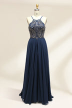 Photograph of a sleeveless, floor-length navy blue gown on a dress form. The gown features intricate beadwork and sequin embroidery on the bodice, with a sheer, flowing skirt. The dress form is positioned against a plain white background, highlighting the elegant and luxurious design of the dress.