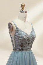 A photograph of a mannequin showcasing a floor-length, light blue tulle gown with intricate silver embroidery on the bodice. The gown has a fitted, sleeveless top and a voluminous skirt. The background is a plain, soft beige, highlighting the gown's elegant and sophisticated design.9133.2