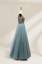 A photograph of a mannequin showcasing a floor-length, light blue tulle gown with intricate silver embroidery on the bodice. The gown has a fitted, sleeveless top and a voluminous skirt. The background is a plain, soft beige, highlighting the gown's elegant and sophisticated design.9133.3