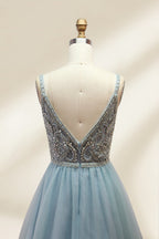 A photograph of a mannequin showcasing a floor-length, light blue tulle gown with intricate silver embroidery on the bodice. The gown has a fitted, sleeveless top and a voluminous skirt. The background is a plain, soft beige, highlighting the gown's elegant and sophisticated design.