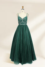 A photograph of a mannequin showcasing a floor-length, sleeveless, dark green evening gown. The gown features a V-neckline embellished with intricate beadwork and a fitted bodice that transitions into a voluminous tulle skirt. The background is plain and off-white, emphasizing the gown's elegant design.9133b.1